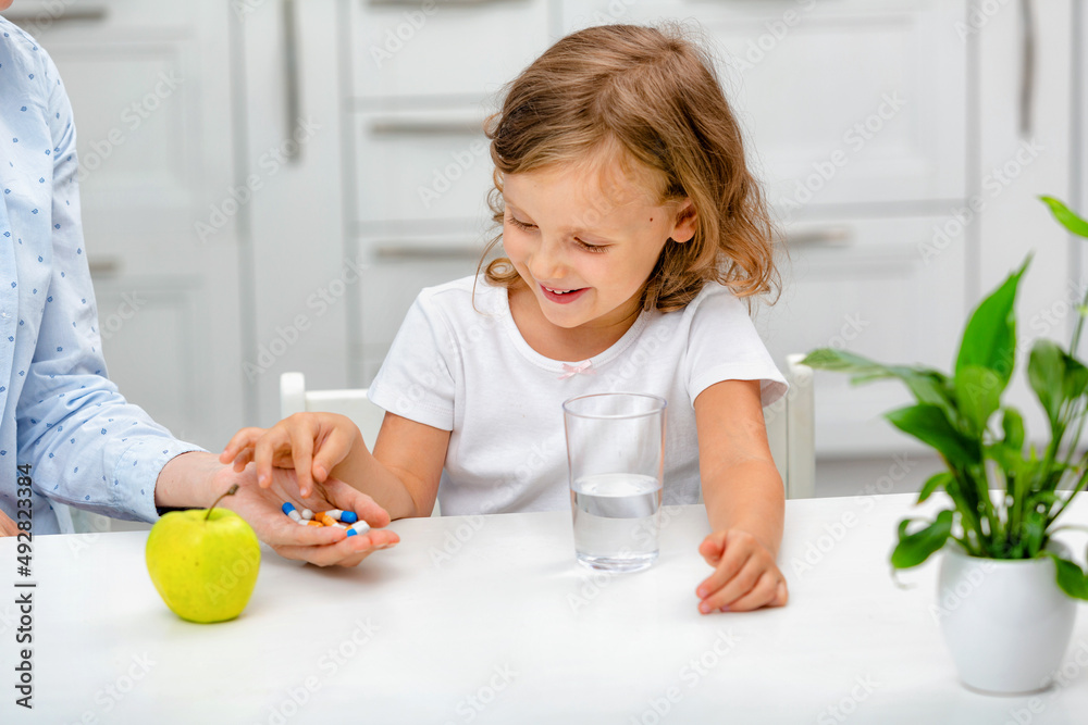 Wall mural a child taking medications, vitamin supplements, nutrition, health care, the mother gives the child 