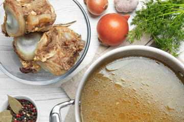 Delicious homemade bone broth and ingredients on white wooden table, flat lay