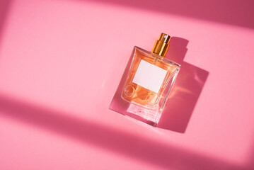 Transparent bottle of perfume with label on a pink background. Fragrance presentation with...