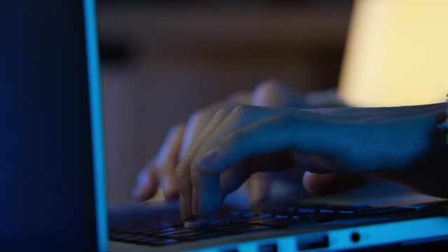 Hands of young woman working with her laptop in the bed in the middle of the night. 4K slow motion.