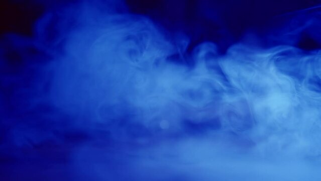The bartender serves a glass of alcohol through the blue smoke