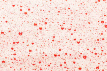 Red soap suds on water, background. Shampoo bubbles.