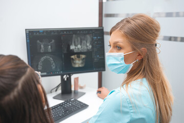 Female dentist is having a talk with her patient while showing the x ray .