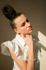 Portrait of a young Ukrainian girl in a white dressYoung beautiful Ukrainian woman sitting on the floor on a round rug looks to the mirror hair gathered in a stylish hairstyle has brown eyes beautiful