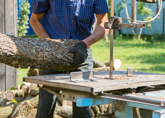 A lumberjack cuts wood on a band saw