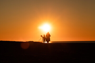 Un mère et son enfant qui tient un cerf volant admirant un coucher de soleil face à la mer à Ostende en Belgique. 
