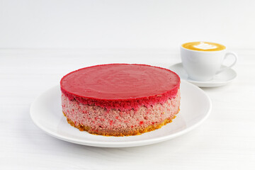 Homemade raspberry and strawberry cheesecake and cup of coffee cappuccino on white wooden table. Copyspace.