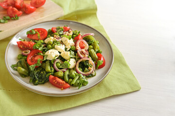 Green vegetables like peas, beans and spinach with feta cheese, braised onions and tomatoes, healthy meal for a vegetarian low carb diet, copy space, selected focus