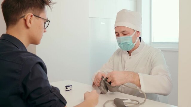 A doctor in latex gloves using a pulse oximeter measures the level of oxygen in the patient's blood in a medical office. Prevention, treatment and health control.