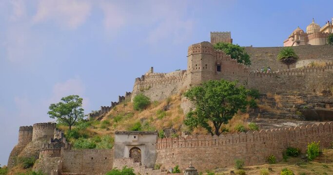 Tourists visit historic Indian Kumbhalgarh fort. Old fortress ancient walls on green Aravalli hills is famous tourist destination. Belongs to Hill forts of Rajasthan. India. Horizontal pan
