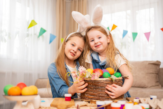 a happy little girls with rabbit ears hold basket with painted eggs