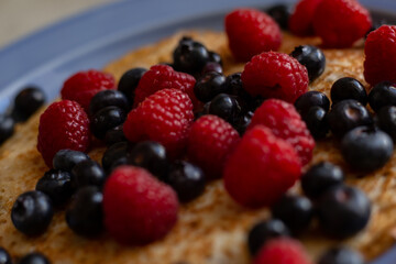 plate with pancakes and berries on a wooden table