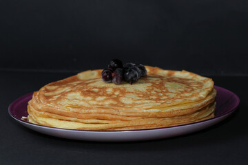 Delicious fried pancakes with frozen currants isolated on a black background. A great treat for Shrovetide