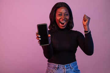 young black woman showing her phone screen rejoices