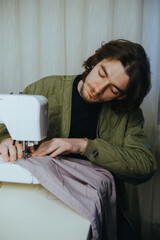 man sews on a typewriter at home