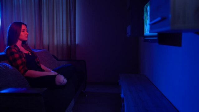  girl sitting on a sofa watching a movie on TV