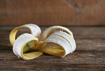 A banana peel lies on a wooden brown table..Zero waste concept. Raw materials for compost.