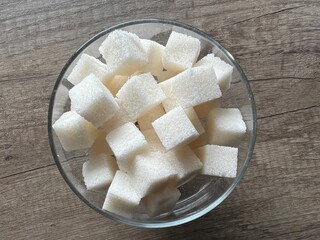 Cubes of white sugar are stacked in a sugar bowl on the kitchen table