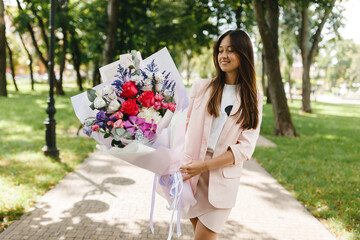 A young European girl is holding a bouquet. Delicate bouquet with red roses and eucalyptus. - Powered by Adobe