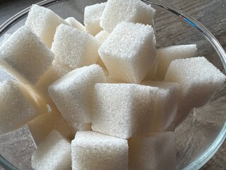 Cubes of white sugar are stacked in a sugar bowl on the kitchen table