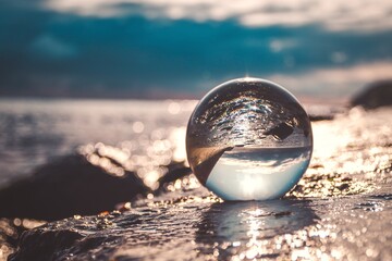 Abstract holiday seaside idea. Sea landscape held in a glass ball with a blurred background.