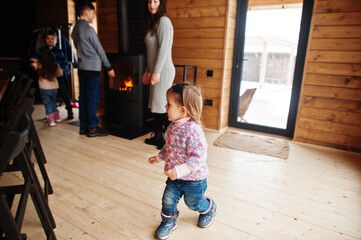 Mother and four kids in modern wooden house against fireplace, spending time together in warm and love.