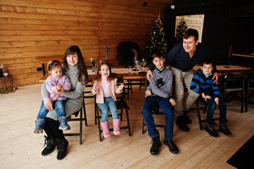 Obraz na płótnie Canvas Family in modern wooden house sitting against table with christmas tree, spending time together in warm and love.