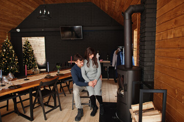 Couple in modern wooden house spending time together near fireplace in warm and love.