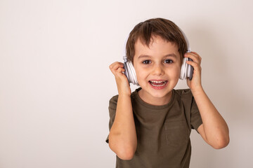 a little brunette boy listens to music with headphones and laughs