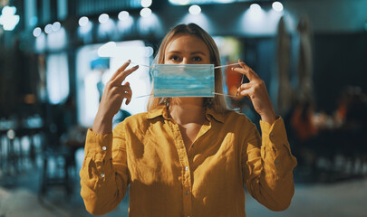 Woman putting on a medical mask on the street. Wear mask in public place.