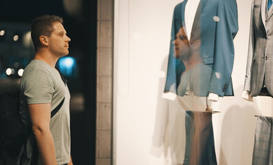 Man looking at the shop window of clothing store.
