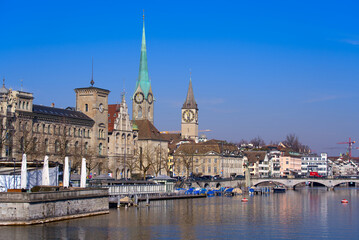 Fototapeta premium Skyline of the medieval old town of Zürich with river Limmat in the foreground on a sunny spring day. Photo taken March 3rd, 2022, Zurich, Switzerland.
