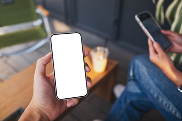 Mockup image of a man holding mobile phone with blank white screen with a woman using smart phone...