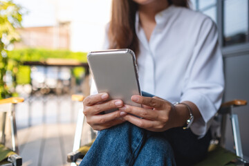Closeup of a young woman holding and using mobile phone