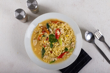 a bowl of hot noodle with boiled egg, chicken, slice chili in white bowl on white background texture