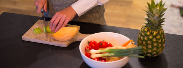 Woman chef cutting vegetables on the cutting board in the kitchen