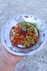 closeup the fried peas,cauliflower,red carrot, with mint and wild flower sous vegetable made i the steel plate over out of focus grey background.