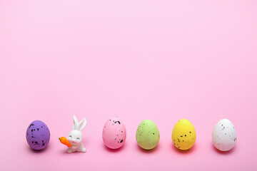 easter colorful eggs stand in row and between them easter bunny on a pink background, space for text, concept greeting easter card