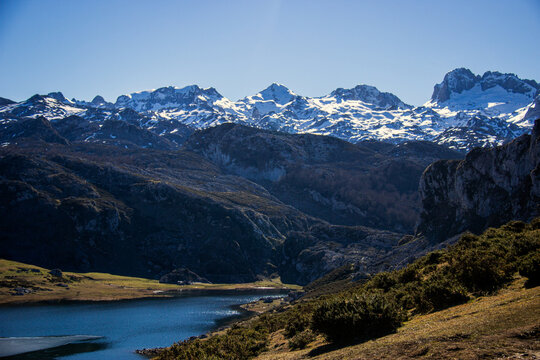 Paisaje monta&ntilde;oso nevado adornado por un lago semicongelado . Cielo azul y setos verdosos .Lagos de Covadonga 