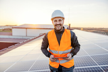 A happy worker testing solar panels with tablet.