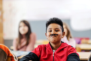 A silly Indian boy making jokes and pretending a pencil is a mustache.