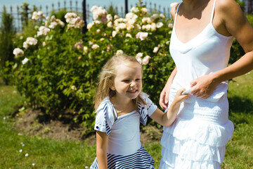 young pretty woman with cute daughter in rose garden at summer happy smiling, lifestyle people concept