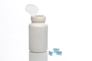 Concept. White plastic medicine bottle with open lid. There are three blue tablets. Reflection. Isolated on white.