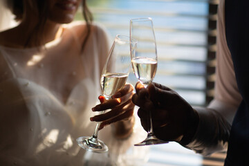 Two glasses with sparkling champagne wine in hands of newlyweds in the wedding day.