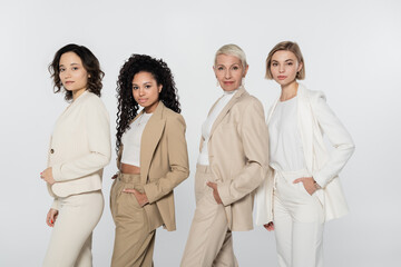 Multiethnic businesswomen in formal wear posing isolated on grey, feminism concept.