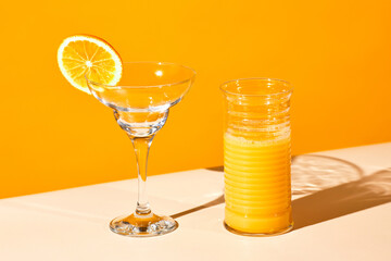 Vibrant still life of orange juice and water glass against colored background, copy space