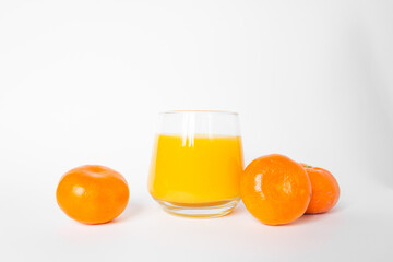 Glass of fresh orange juice with three citrus mandarin fruits near. Isolated on the white background.