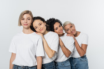 Obraz premium Positive multiethnic women hugging each other and looking at camera isolated on grey.