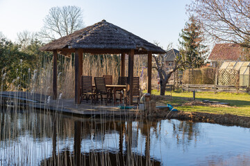 Fototapeta na wymiar Wooden gazebo in a garden overlooking a pond