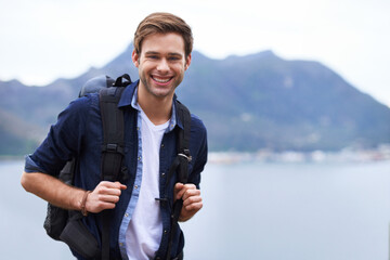 Best hiking destination. Portrait of a handsome young man standing with a backpack in the outdoors.